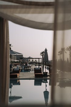 Elegant resort pool view with sunbeds and palm trees under a clear sky.