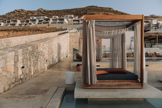 A luxurious cabana by the poolside at a hillside resort, offering a serene relaxation spot with stunning architectural views.