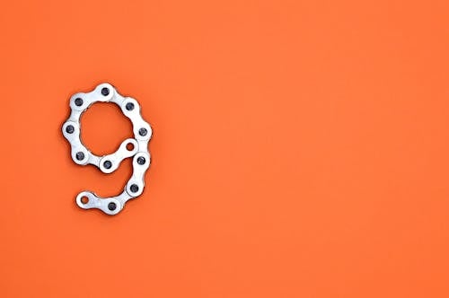 Free Gray Bicycle Chain on Orange Surface Stock Photo