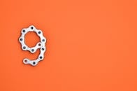 背景为充满活力的橙色，带有复制空间，形状像数字9的金属链