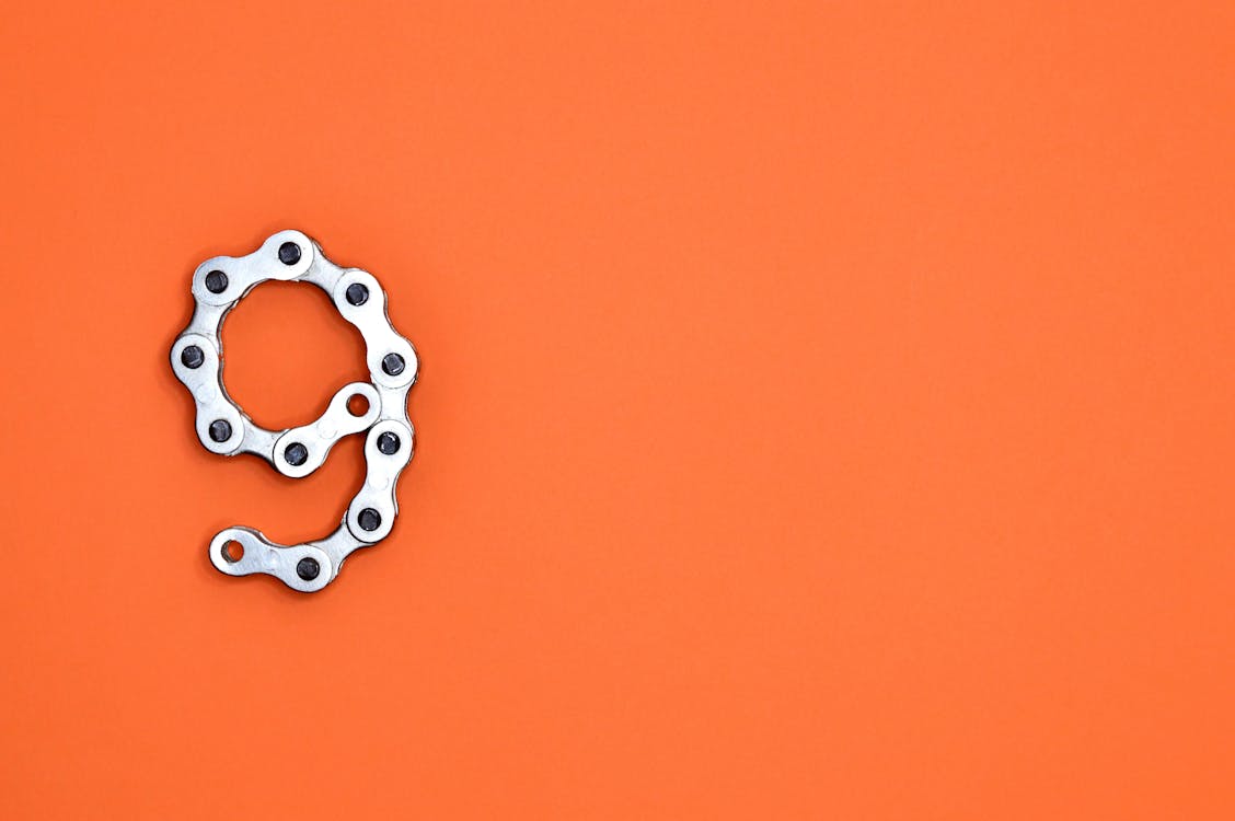 Free Gray Bicycle Chain on Orange Surface Stock Photo