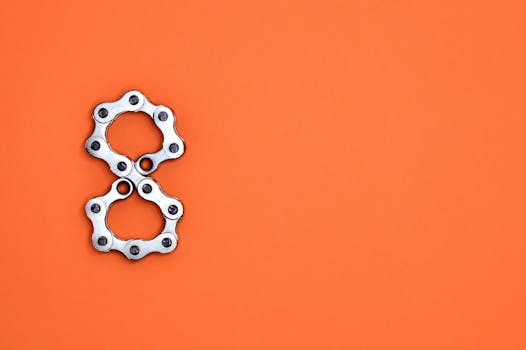 Creative arrangement of bicycle chain links in the shape of the number eight on a bright orange background.