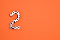 亮橙色背景上的金属链形成数字2，非常适合设计项目