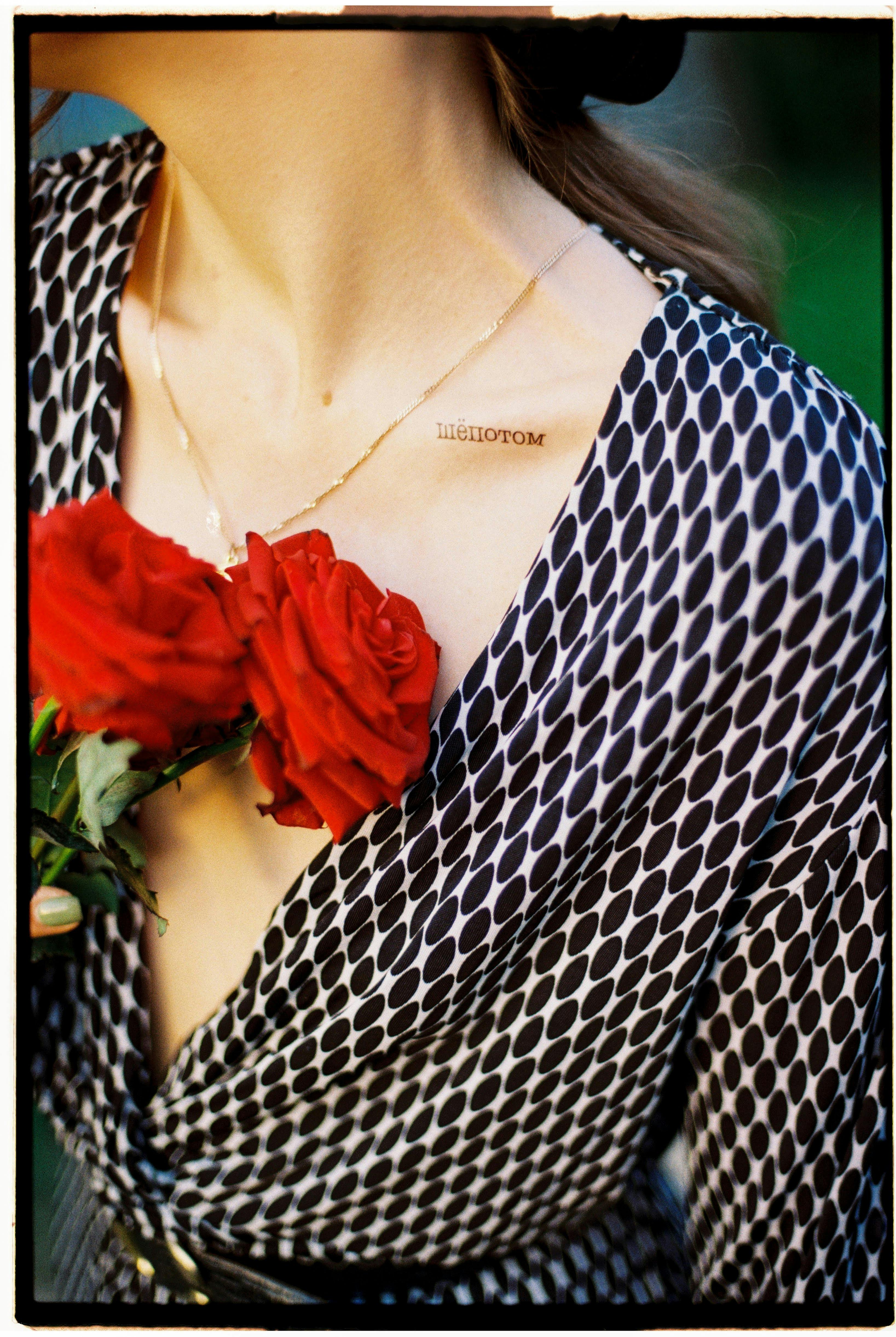 Close-up of a woman in a polka dot dress holding vibrant red roses.