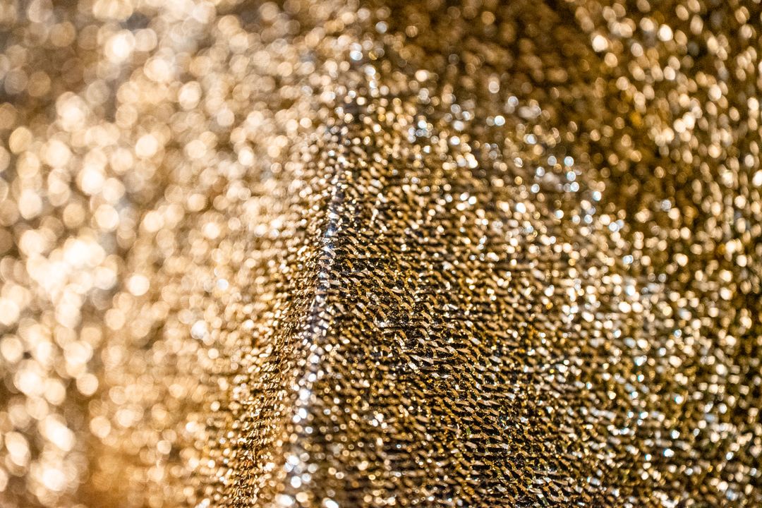 Close-up of shimmering gold fabric with a textured pattern, creating a luxurious and abstract background.