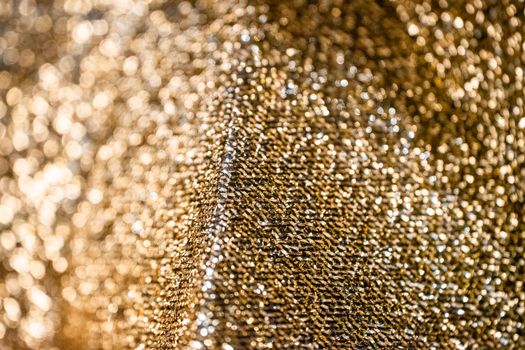 Close-up of shimmering gold fabric with a textured pattern, creating a luxurious and abstract background.