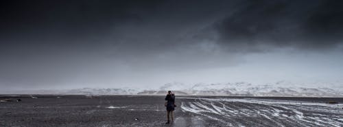 Free Man Standing on Gray Dessert Under Gray Cloudy Sky during Daytime Stock Photo