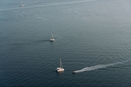 Free A serene aerial view showing boats on a calm ocean surface, ideal for travel and nature concepts. Stock Photo