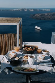 Morning breakfast with a sea view, featuring pastries and drinks on a balcony.