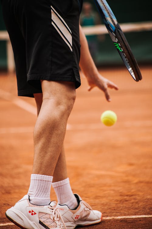 Person in Black Shorts and White Socks Holding Black Tennis Racket