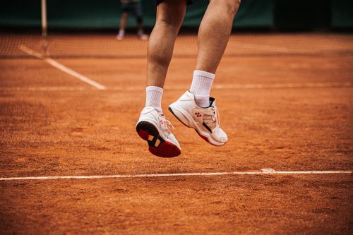 Free Low angle view of a tennis player jumping on a clay court, showcasing movement. Stock Photo