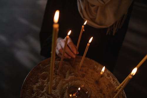 A Person in Black Long Sleeve Dress Holding Yellow Candle