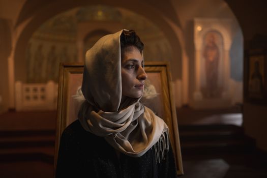 A woman in a headscarf amidst a serene church interior, reflecting spirituality.