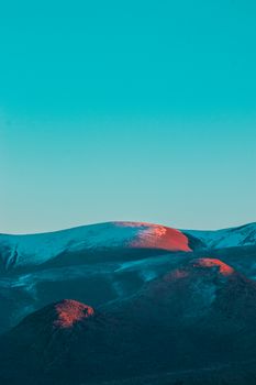A breathtaking aerial view of Niğde mountains bathed in warm sunrise light under a clear blue sky.