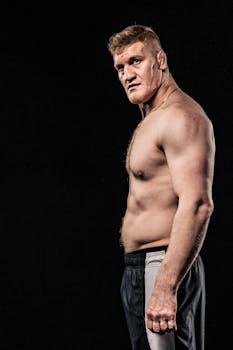Side profile of a muscular man posing confidently against a black background.