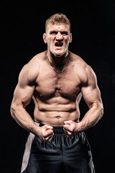 Shirtless bodybuilder showing muscular physique, expressing strength against a black background.