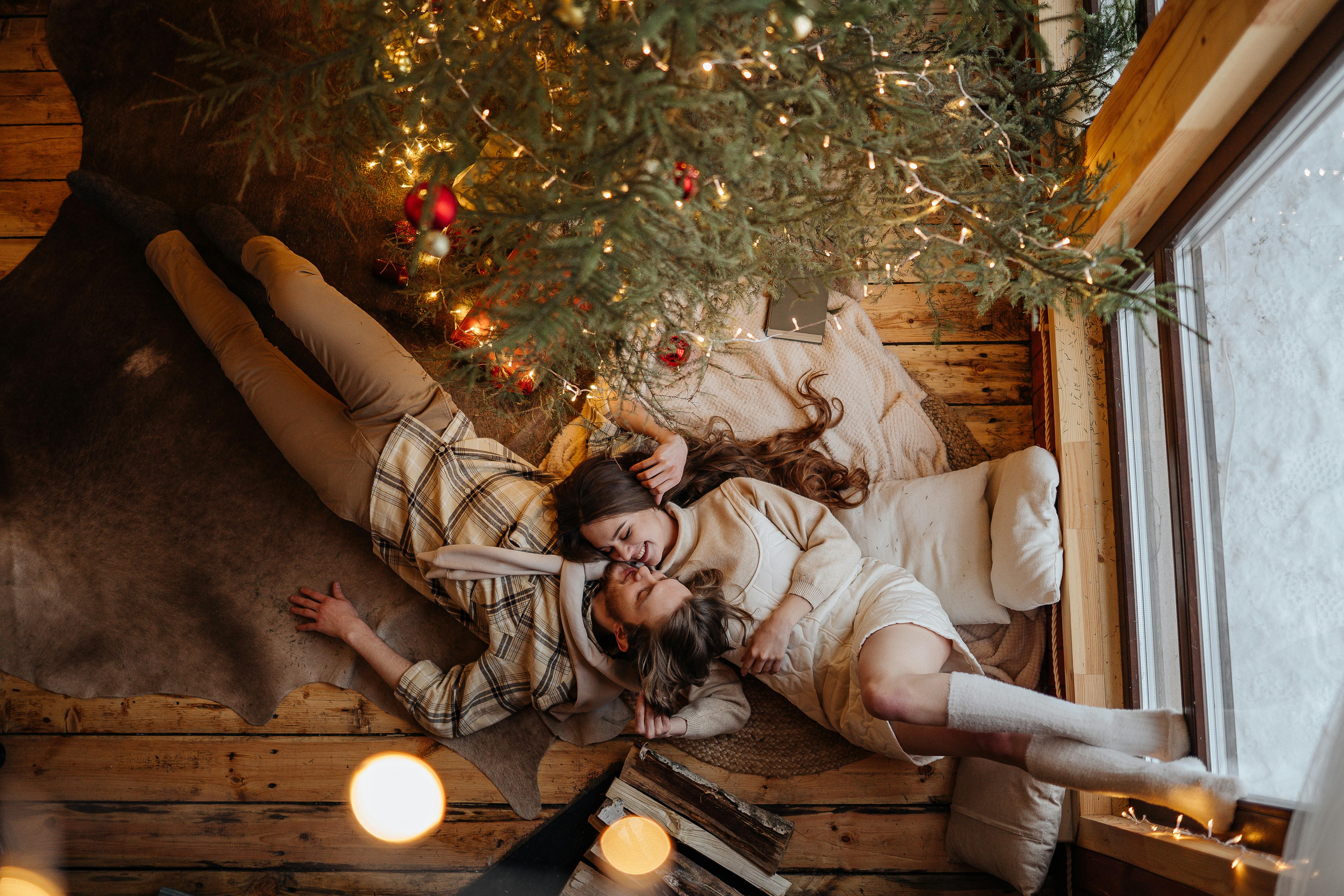 couple lying on carpet and christmas tree