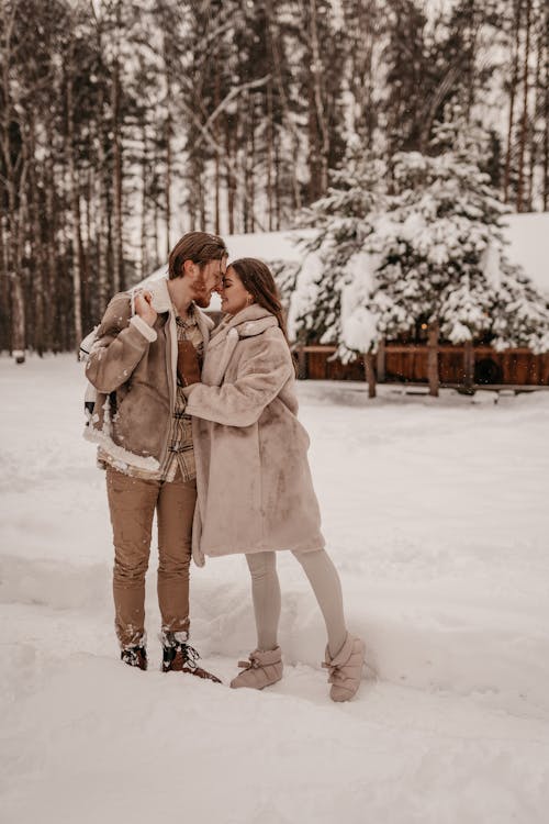 Couple in Warm Clothes Hugging Against Trees