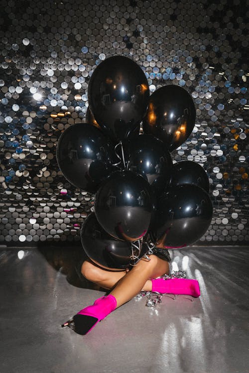 Woman Sitting on the Floor Holding a Black Balloons 