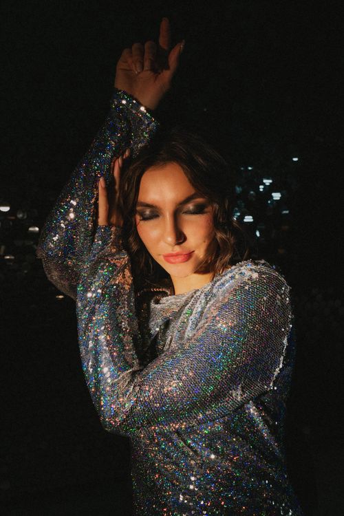 Free A stylish woman in a glittery outfit poses with closed eyes in a trendy studio shoot. Stock Photo
