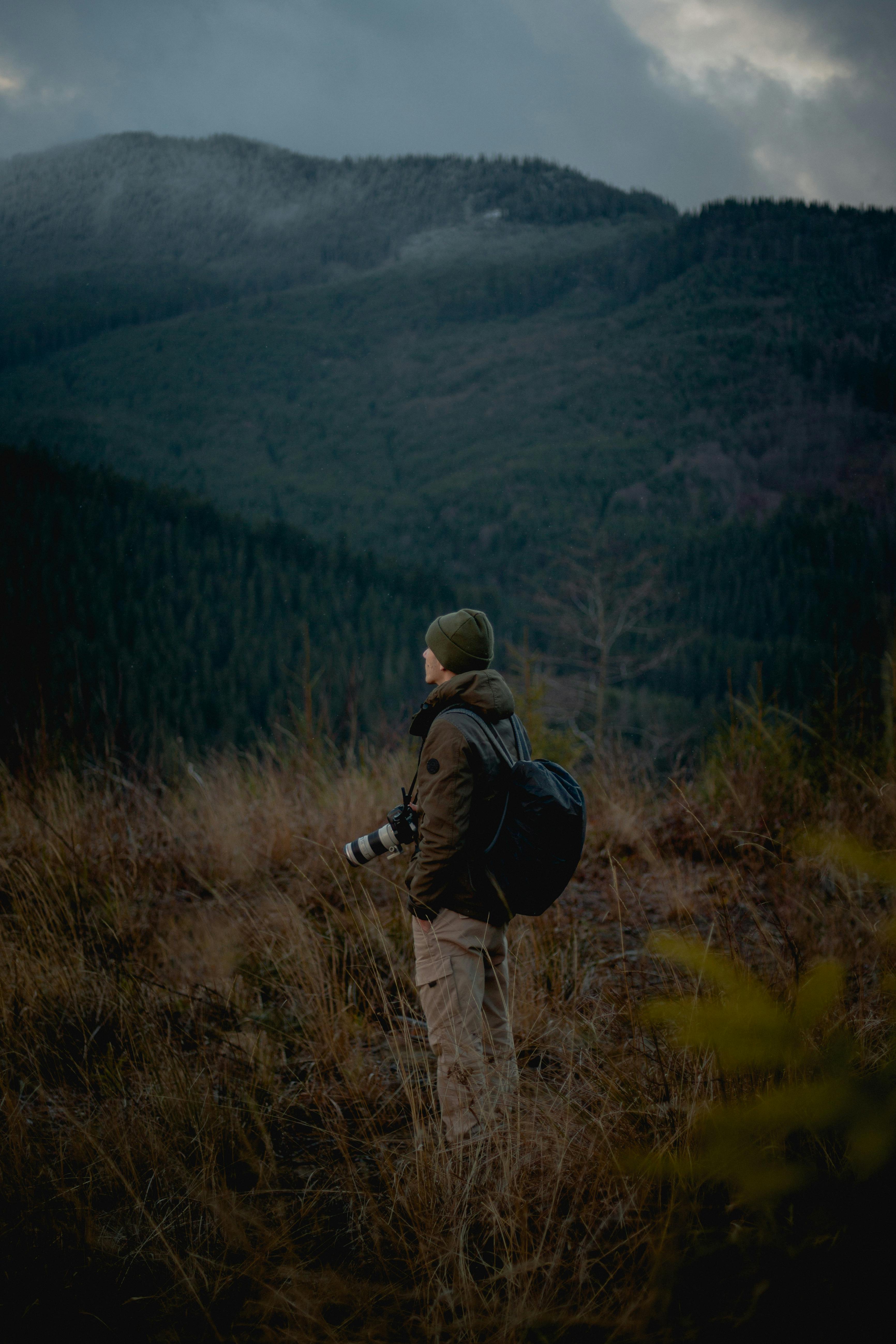 A nature photographer observes the mountainous wilderness, capturing the serene landscape.