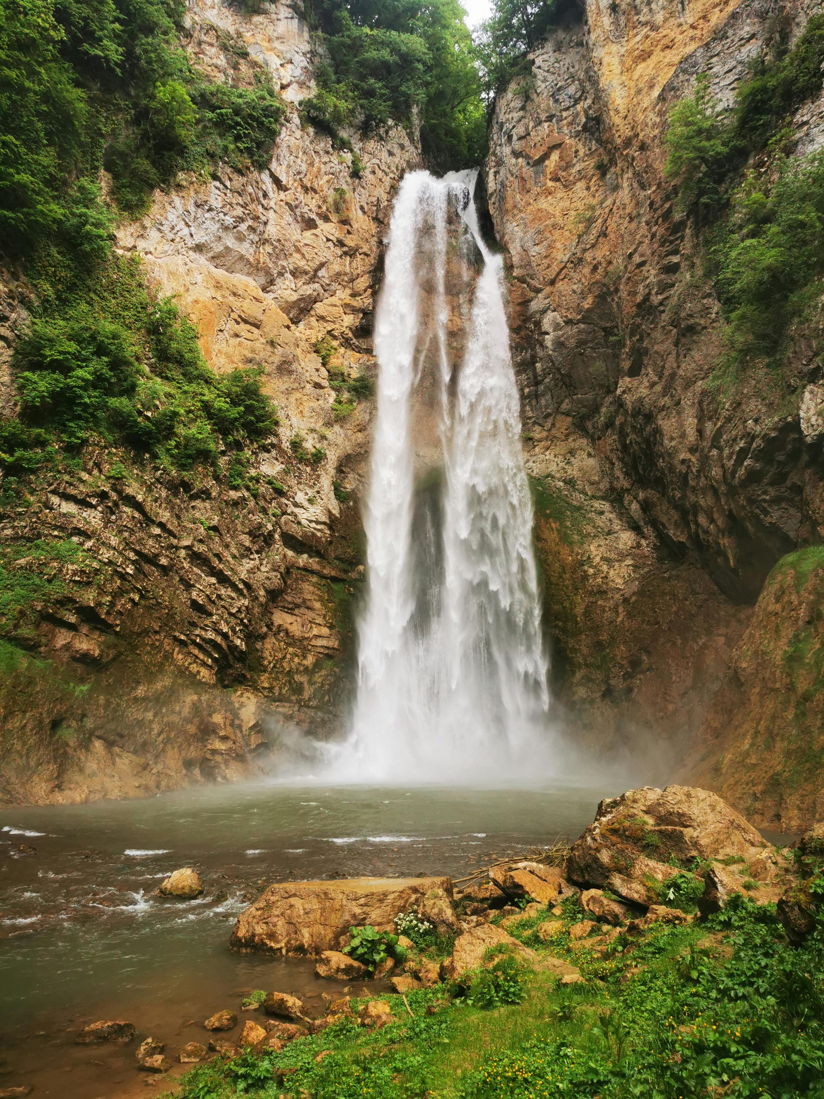Captivating waterfall cascading down rocky cliffs surrounded by lush greenery.