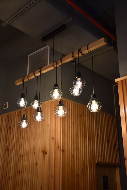 Free Stylish pendant lights hanging in a wooden-themed interior setting, creating a warm ambiance. Stock Photo