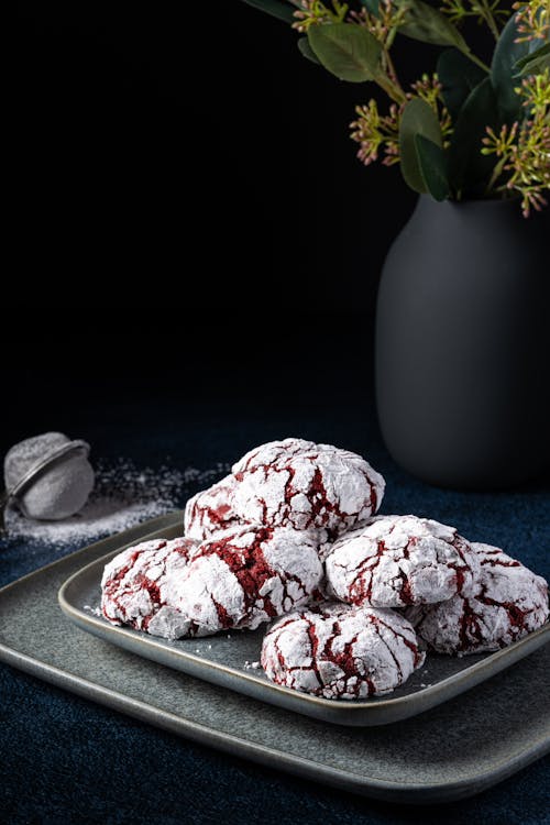 Red Velvet Cookies Coated in Icing Sugar Served on Black Plate