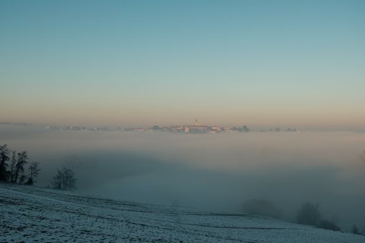 A serene winter landscape featuring a misty town under a foggy sky, embodying tranquility.