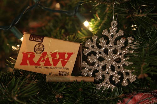 Close-up of a Pack of Rolling Papers and a Joint beside a Christmas Decoration