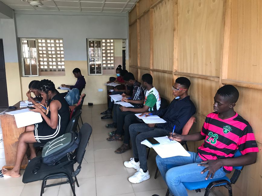 A diverse group of teenagers focusing on studies in a classroom environment, seated in a row.