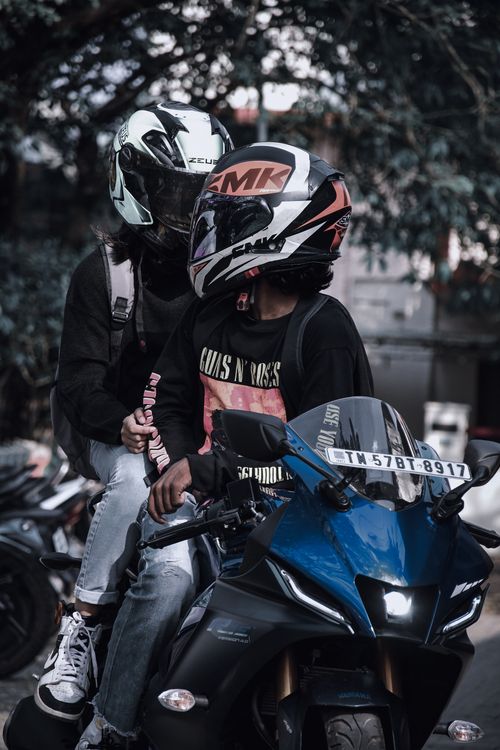 Free A couple wearing helmets rides a motorcycle together on an urban street. Stock Photo