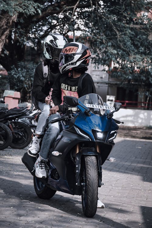 Two People in Helmets Seated on Motorcycle in Street