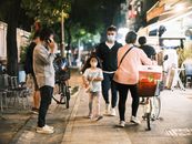 Urban street at night with people wearing face masks, depicting a scene of the new normal.