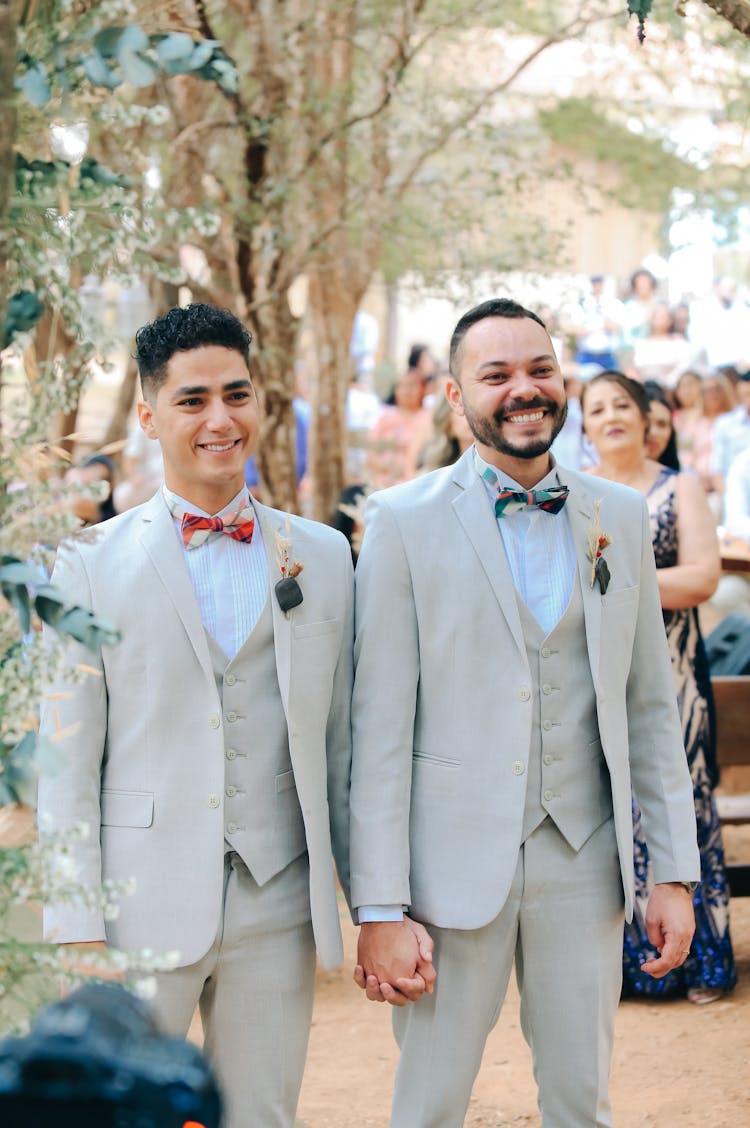 Two Men In Pale Blue Suits Standing Together And Holding Hands