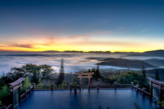 Beautiful sunrise over a misty mountain valley with traditional shrine gates.