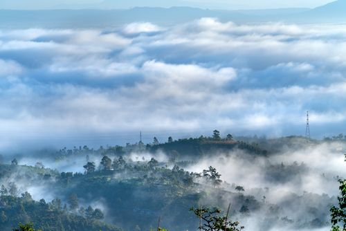 Free Stunning vista of mist-covered hills emerging through a sea of clouds, creating a serene landscape. Stock Photo