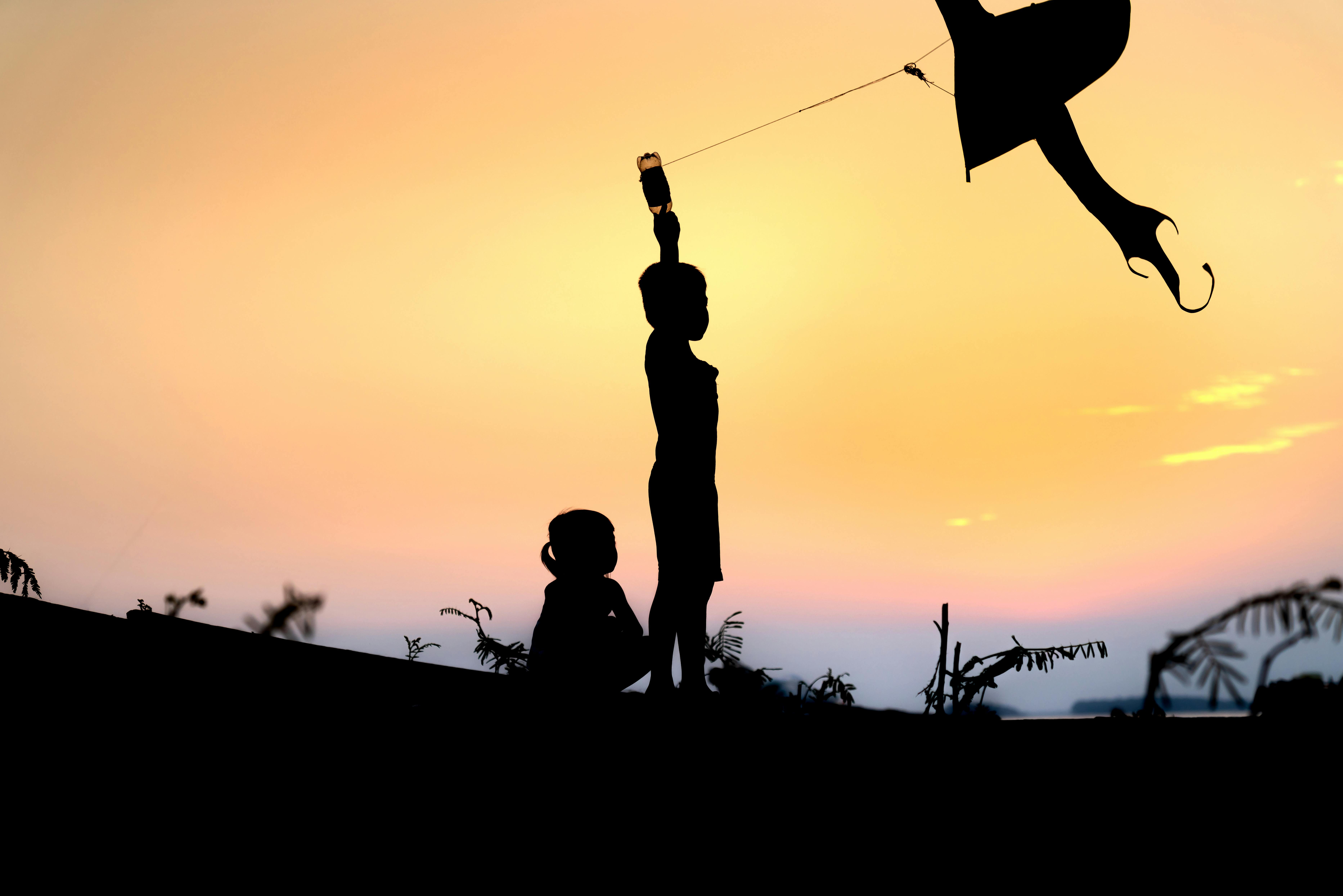 Fishing village children play kite flying at sunset, silhouette Stock Photo  - Alamy