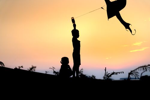 Free Silhouette of children flying a kite at sunset, capturing joy and playfulness. Stock Photo