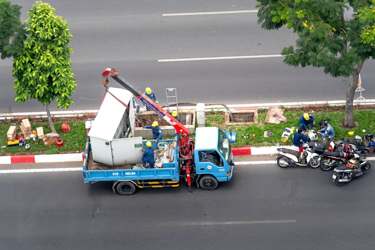 Men Dismantling Transformer Standing Between Street Lanes