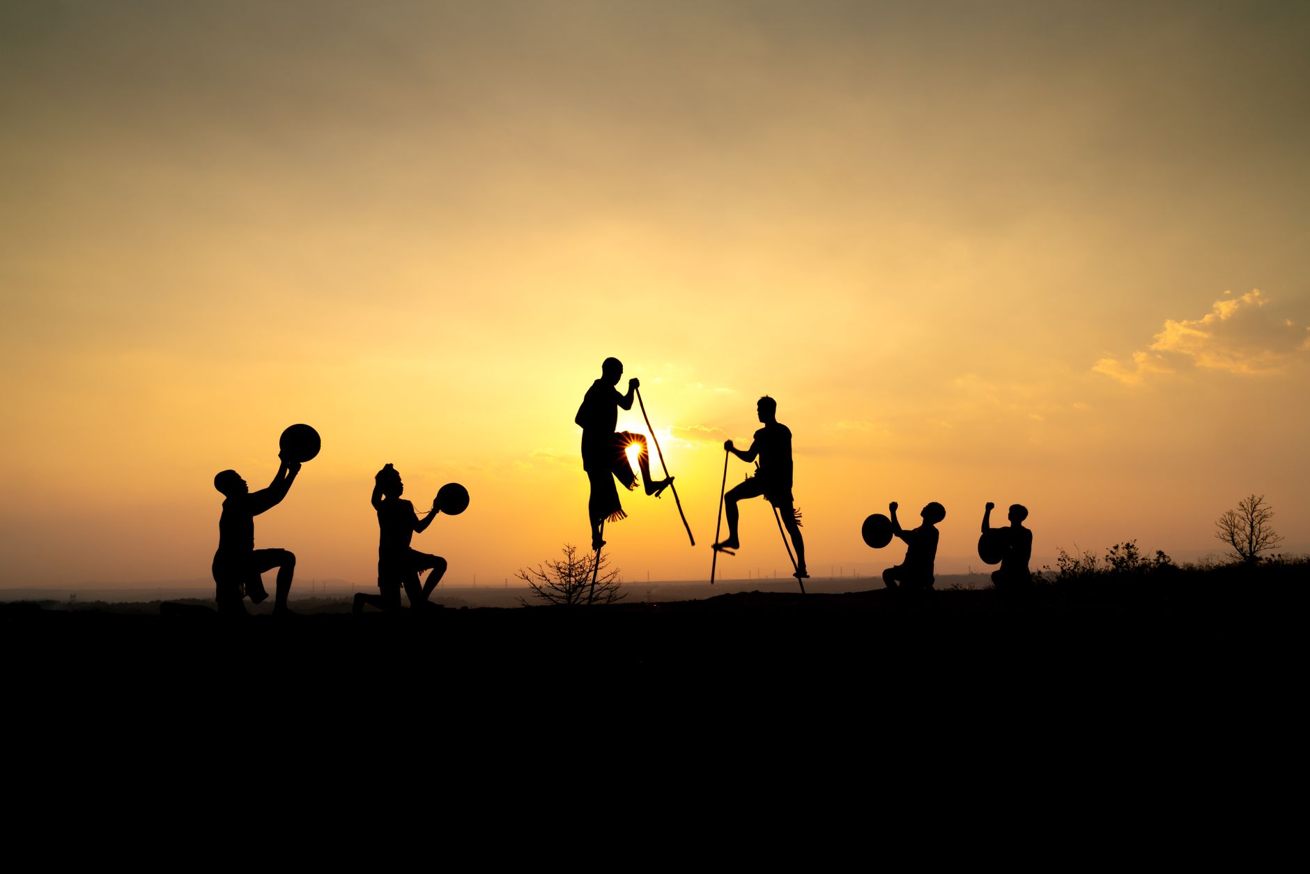 stilt walkers hire egypt — Silhouetted group of performers with instruments and stilts at sunset.