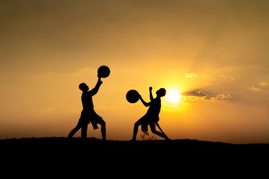 Silhouetted figures performing theatrics against a vibrant sunset sky.