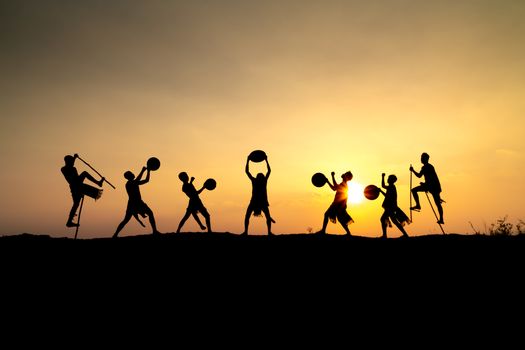 Silhouetted figures dance and perform in vibrant sunset backdrop, creating a dramatic scene.