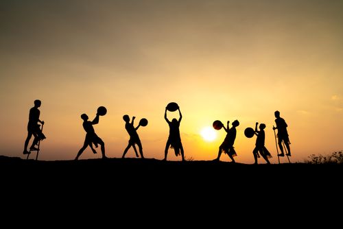 Free Silhouettes of people performing with drums against a vibrant sunset. Stock Photo