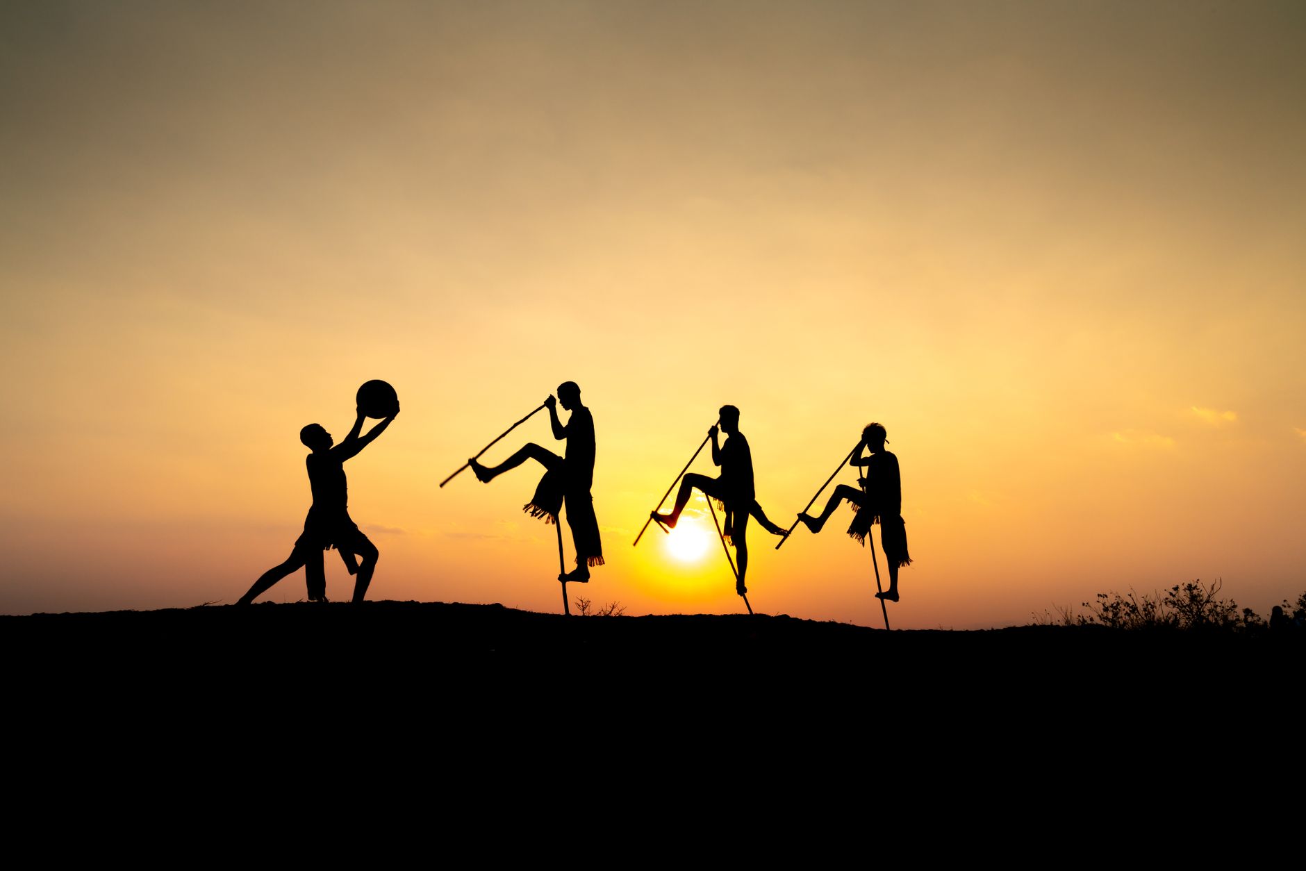 stilt walkers hire egypt — Silhouetted figures on stilts enjoy a sunset stroll, captured in vibrant colors.