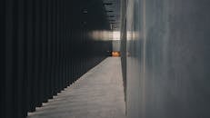 探索一条狭窄昏暗的走廊，现代建筑元素与柔和的光线反射交织其间