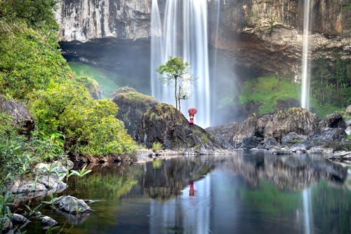 A Person Standing on a Rock Near Waterfalls