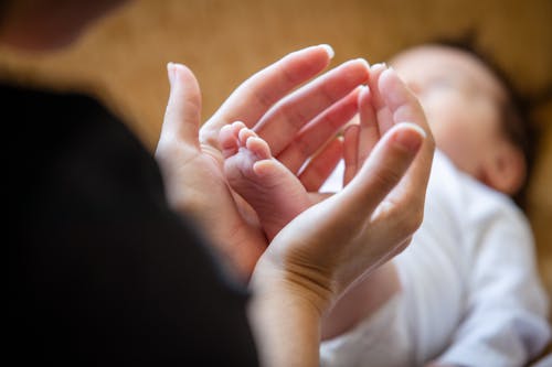 Free Close-up of Mother Holding the Foot of Her Newborn Baby  Stock Photo