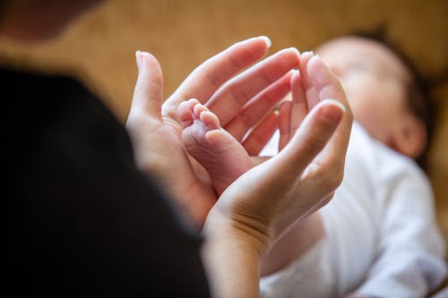 Close-up of Mother Holding the Foot of Her Newborn Baby 