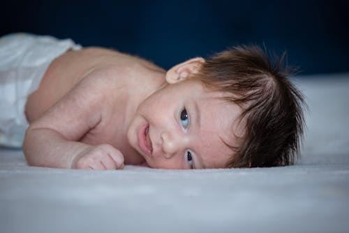 Free Shirtless Baby Lying on White Textile Stock Photo